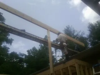 Carpenter setting a ridge beam over a new addition frame — Ice Dam Removal by Roofing Brothers in Point Marion
