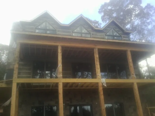 Dormers and porch framing on a large log home under construction — Roof Coating work by our crew in Point Marion