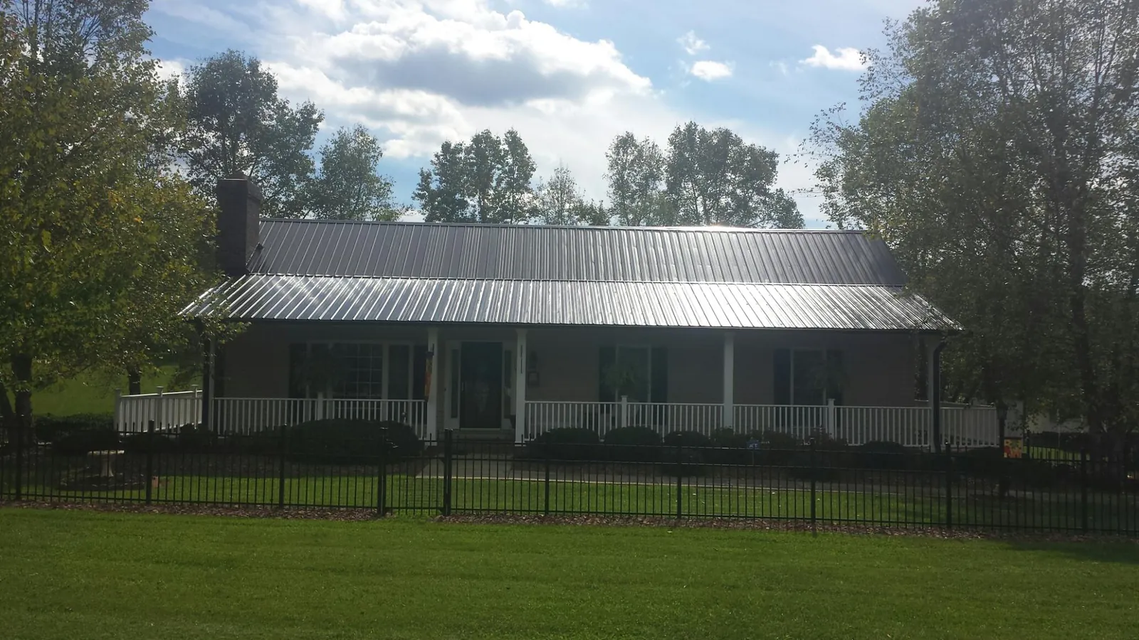 Gray metal roof on a brick ranch with a full width front porch — Gutter Guard Installation work by our crew in Point Marion