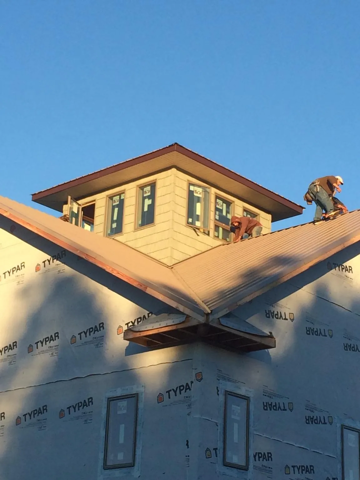Roofers working around a rooftop cupola on a new metal roof at sunset — Roof Waterproofing in Point Marion by Roofing Brothers